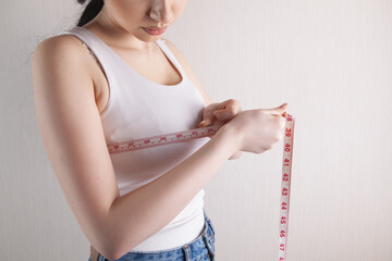 Slim woman measures her breast with a measuring tape