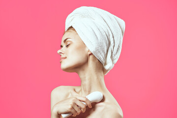 attractive woman with towel on head face massage relaxation pink background