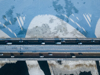 Kyiv metro bridge. A shadow falls on the frozen Dnipro river. Aerial drone view. Winter sunny morning.