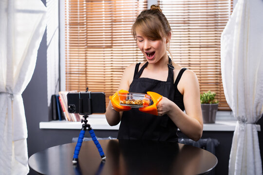Young woman cooking at home while broadcasting online for home webinar masterclass lesson - Woman makes videos preparing vegetarian meal - Food concept