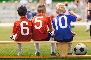 Children in Sports Team. Happy Kids in Sportswear with Ball Sitting on Soccer Football Bench....