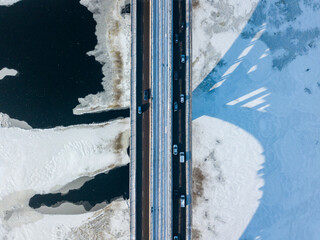 Kyiv metro bridge. A shadow falls on the frozen Dnipro river. Aerial drone view. Winter sunny morning.