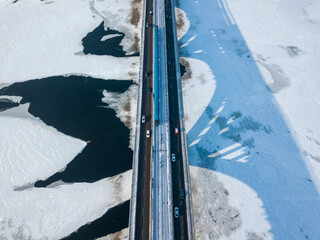 One metro train travels along the Kiev metro bridge. A shadow falls on the frozen Dnieper River. Aerial drone view. Winter sunny morning.