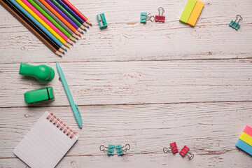 Homeschool supplies laid out on a rustic white wooden table including pencils, notebook, paper clips all ready for home school with copy space and room for text