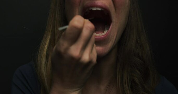 A young woman is taking a sample from her mouth with a swab for a corona virus test