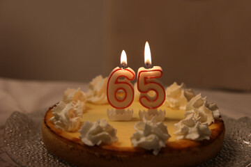 Closeup of a birthday cake with 65 candles on it on the table