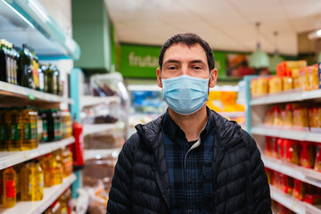 Young man wearing face mask buying food at supermarket. Coronavirus concept.