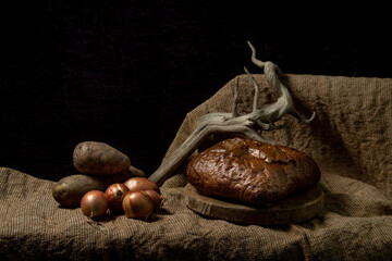 Black bread and vegetables on a black background. Borodino bread. Homemade baking. Bakery product....