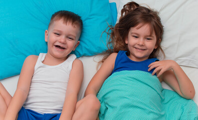 Children fool around in bed.Close-up of happy children playing at home on the bed. The concept of family holiday weekend