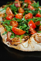 Pinsa romana gourmet italian cuisine on black background. Scrocchiarella traditional dish. Food delivery from pizzeria. Pinsa with meat, arugula, tomatoes, cheese.