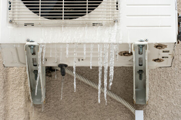 The outdoor unit of the air conditioner is covered with ice and icicles. External split wall of the air conditioner. the compressor unit is installed outside the building.