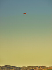 Paraglider flying in blue sky.