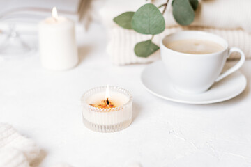 Details of still life in the home interior of living room. Cup of coffee, cotton, book, candle, sweater. Moody. Cosy autumn winter concept on white background. Decoration.