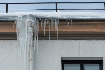 The drainpipes are covered with ice and snow. After a heavy snowstorm, the city is covered with...
