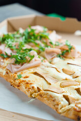 Pinsa romana with pear, cheese, prosciutto in delivery box. Scrocchiarella gourmet italian cuisine on white background. Holding traditional dish. Food delivery from pizzeria.