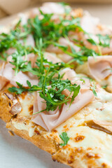 Pinsa romana with pear, cheese, prosciutto in delivery box. Scrocchiarella gourmet italian cuisine on white background. Holding traditional dish. Food delivery from pizzeria.