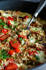 Groats with eggplant and cherry tomatoes in a pan, sprinkled with dill