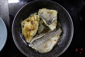 Delicious roast dorado or sea bream fish with lemon and orange slices, spices, and rosemary on baking sheets on wooden table