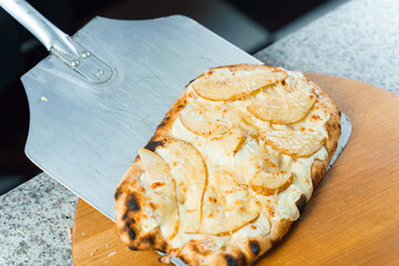 Chef cooking pinsa romana with pear, cheese, prosciutto in delivery box. Scrocchiarella gourmet...