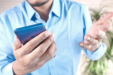 Close up of young man hand using smart phone.