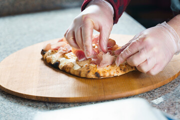 Chef cooking pinsa romana with pear, cheese, prosciutto in delivery box. Scrocchiarella gourmet italian cuisine Holding traditional dish. Food delivery from pizzeria.