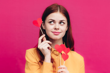 romantic woman in a shirt with hearts on a stick on a pink background