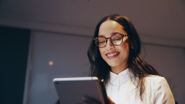 Mixed race business woman laughing and smiling at social media while scrolling on iPad 