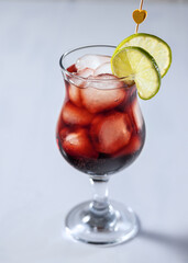 Fresh red alcoholic cocktail with pomegranate syrup, vodka and sprite, ice cubes in glass with cocktail, close up and selective focus