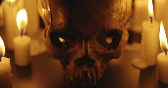 Candles and human skull in darkness closeup footage