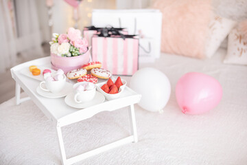 Flowers and sweets on white table and balloons on the white bed. Gift for Valentine's day or March 8 or Mother's Day or birthday