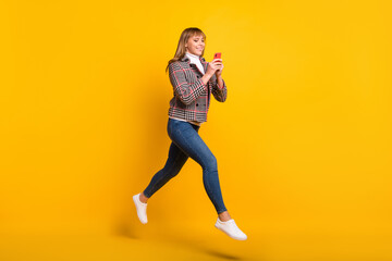 Fototapeta na wymiar Full body profile portrait of carefree pretty blogger typing post comment running isolated on yellow color background