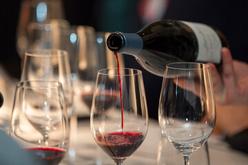 close up on a wine glasses, bottle and red wine being poured