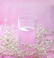 Decorative composition in a monocolor pink shade of a drink in a transparent glass and gypsophila on a watercolor background. © Юлия Глазкова