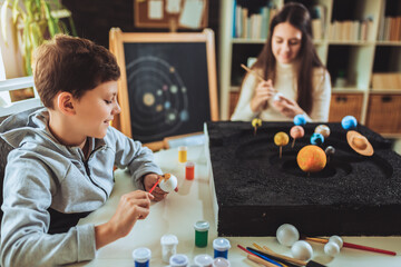 Happy school boy and girl  making a solar system for a school science project at home