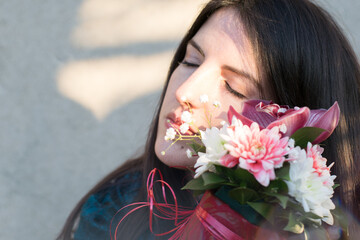 shot of a  young woman black hair  holding a bouquet of flowers roses  in front of her face
