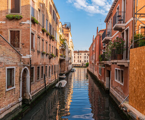 Fototapeta na wymiar View of calm canal and cozy street with flowers on the balconies of the residential area of Venice, Italy.