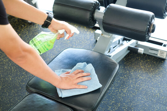 partial view of man cleaning sports equipment in gym on blurred foreground