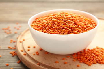 Red lentils in white bowl on a grey wooden table.