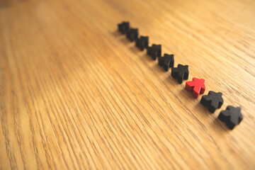 Red person stands out from a crowd of people on a wooden table. Leadership, uniqueness, independence, initiative, strategy, think differently, business success concept