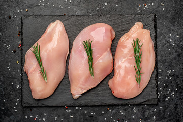 raw chicken breast on a cutting board with spices on a stone background