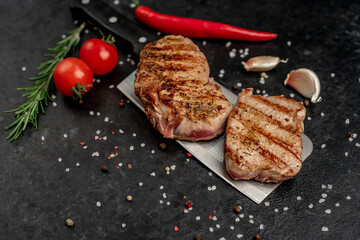grilled beef steak on a knife on a stone background