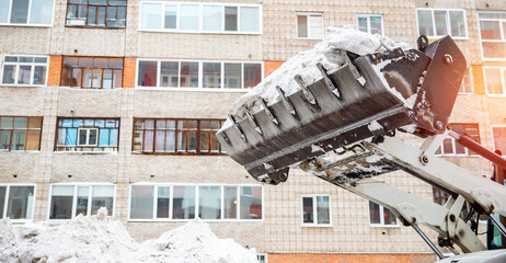 Snow removal excavator tractor cleaning on winter road covered with snow