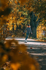 Girl sits on a skateboard.Aerial view of road in autumn with colorful trees. Drone photography.