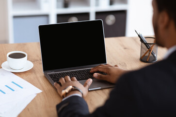 Black businessman hands typing on laptop with blank screen