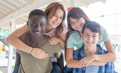 Obraz premium Two couple of teenagers having fun piggybacking at school