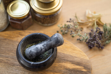 Alternative medicine concept - dry herbs, mortar on wooden table