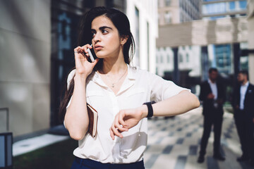 Fototapeta premium Thoughtful ethnic female speaking on smartphone