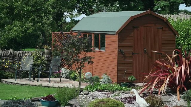 Garden shed with Dutch style roof on a warm summers day in country garden.
