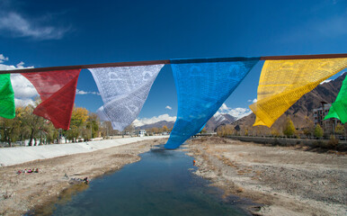 Prayer flags over the river with snow-capped mountains at a distance. Lhasa, Tibet, China