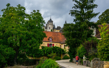 Fototapeta na wymiar Pequeño castillo de Monfort, con algunas construcciones del pueblo cercano, enmarcada por la vegetación de la comarca de la Dordoña